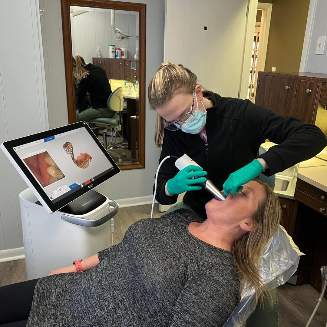 Female dental professional using a Primescan Scanner machine on a patient