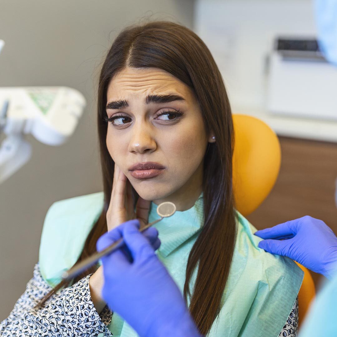 Young Woman Holding Cheek In Chair At Dentist, Having Toothache. Shot Of A Young Woman Suffering From Toothache While Sitting In The Dentist"u2019s Chair